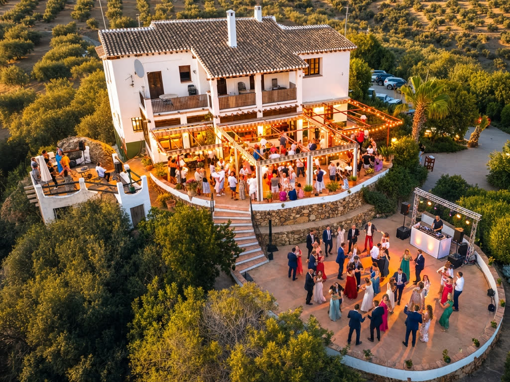 Aerial view of a wedding reception at Finca Cantueso, guests dancing on the terrace at sunset with the Andalusian olive groves beyond